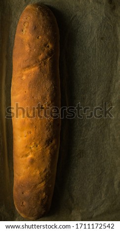 
A freshly made loaf of bread on kitchen paper. Vertical format. Aerial view.