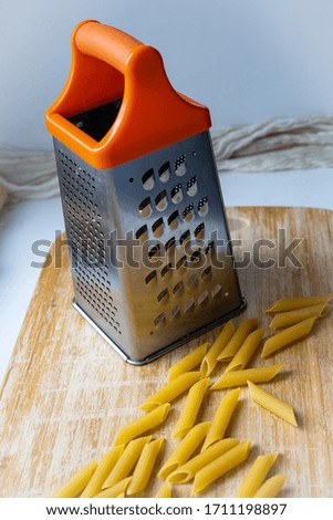 metal stainless steel vegetable shredder with orange holder on wooden cutting board