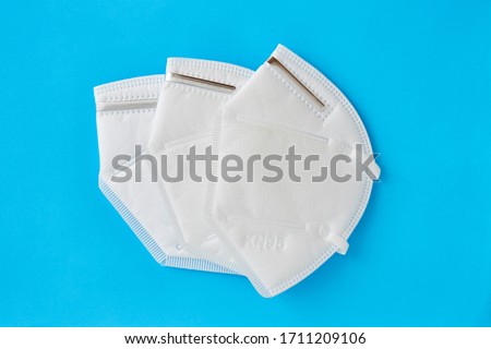 Set of three KN95 FPP2 disposable medical respirator white mask medical equipment on blue background.  Royalty-Free Stock Photo #1711209106