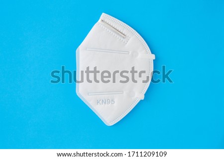 KN95 FPP2 disposable medical respirator white mask medical equipment on blue background.  Royalty-Free Stock Photo #1711209109