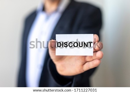 DISCOUNT word on sticker in man's hand with blurring background of man in suit