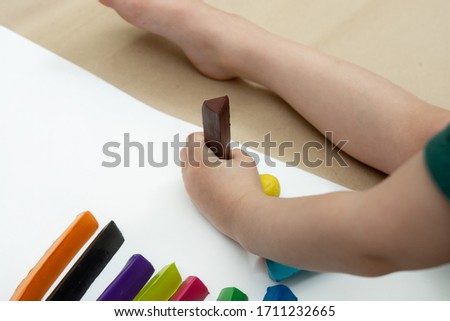 little boy holds a piece of plasticine in his hand. many multi-colored bars on the background lie nearby.