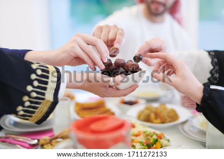 Eid Mubarak Muslim family having Iftar dinner eating dates to break feast. Eating traditional food during Ramadan feasting month at home. The Islamic Halal Eating and Drinking at modern western Islam Royalty-Free Stock Photo #1711272133