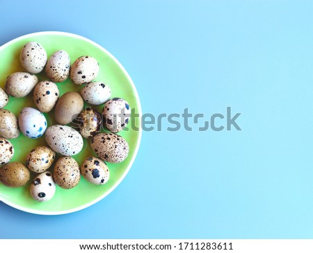 green plate with quail eggs on a blue background. flat lay