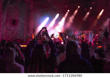 fans at a music concert dance and shoot video on the phone, youth outdoor festival Royalty-Free Stock Photo #1711286980
