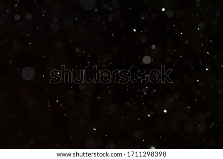 Detail of floating dust particles lit against a black background.