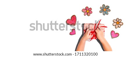 Little boy making a gift box with flowers and hearts drawings overhead view
