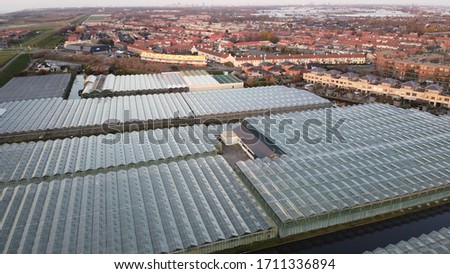 View of greenhouses with a town in the background. Shot on 60 meters altitude.
