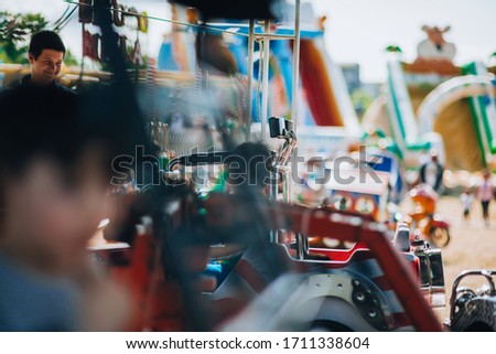 Beautiful boy driving a colorful car toy at the local carnival