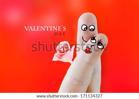 Fingers with sweet faces painted featuring a couple in love celebrating valentines day with a flower