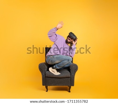 Boy with VR glasses play with a virtual videogame. Yellow background