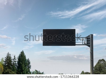 empty black digital road sign with clouds and trees in sunny day 