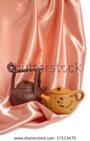 Two chinese teapots on a beige satin background
