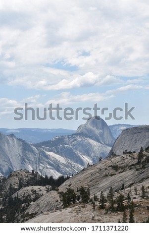 Half Dome in the distance. Trees and mountains in foreground.