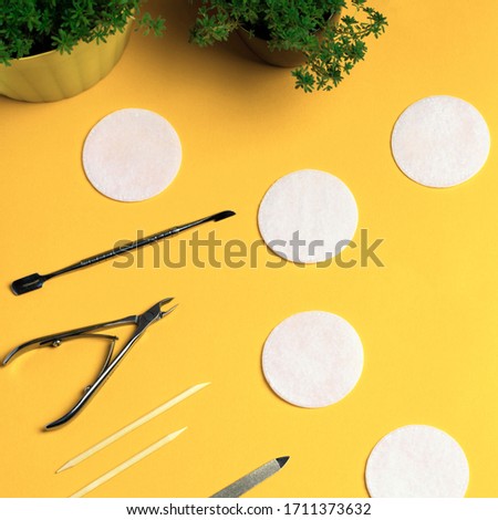 Equipment for manicure and pedicure on a yellow background. Tongs, nail file, pusher, cotton pads. Home manicure.