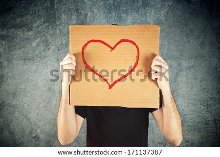 Man holding cardboard paper with heart shape drawing as Valentines day conceptual image.