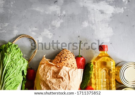 Food donation or food delivery concept. Free space for text. Oil, cabbage, lettuce, vegetables, canned food, bread. Light gray background. Top view.