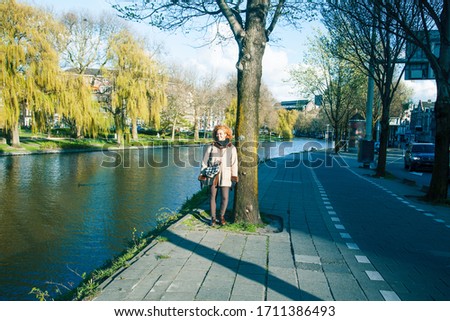 young pretty african american girl with curly hair at water channel in Amsterdam Holland, lifestyle people concept, tourist in european german city