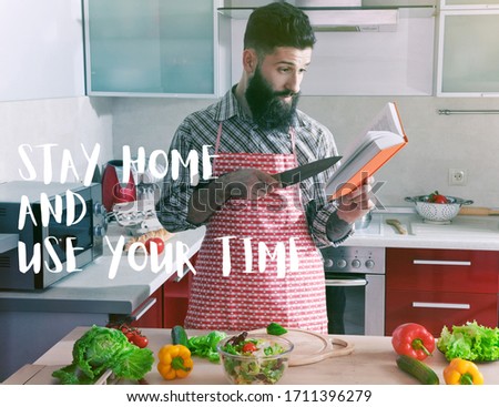 Man cooking at kitchen and reading recipe book. Text Stay home and use your time. Home isolation and quarantine during coronavirus covid-19 pandemic. Royalty-Free Stock Photo #1711396279