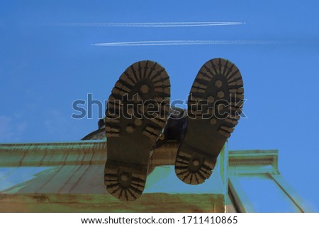 woman wear hiking high boots on  blue sky background. no face. low angle shooting. top of roof. 2 two aiplanes fly in heaven.