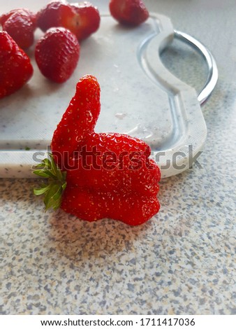 A strawberry in the shape of a hand holding the thumb up. Suitable as an advertisement for strawberry dishes of all kinds.