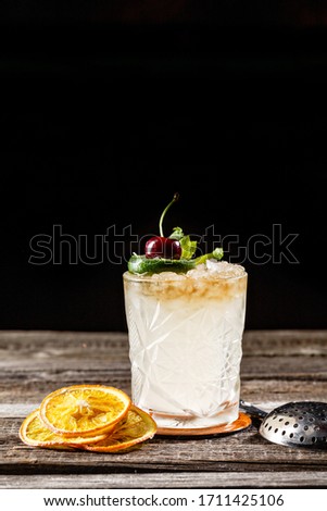 Traditional Mexican beverage in a fancy glass flavored with lime with artistic cherry on top and orange presentation wooden table. Picture best use for Mexican restaurant book menu concept.