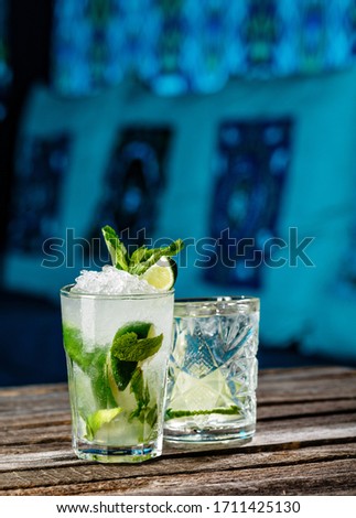 Traditional MOJITO refreshment in a jar and glass flavored with orange, strawberry and lemon in wooden background. Picture best use for Mexican restaurant book menu concept.