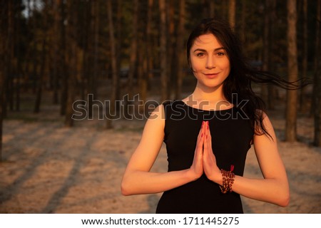 Portrait of a young beautiful girl practicing yoga at sunset on the nature