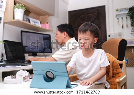 Stay Home Stay Safe, Father and son using computers at home, Coronavirus pandemic prevention, Businessman working from home, kindergarten closed, while in quarantine during the Covid-19 health crisis