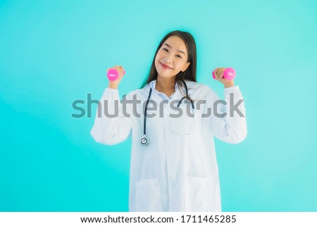 Portrait beautiful young asian doctor woman with pink dumbbell for exercise on blue isolated background