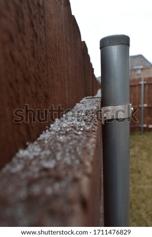 Snow on top of fences, roofs, flowers,and tables