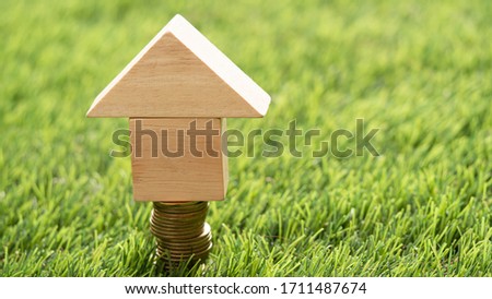 Pieces wooden model stacked as a house put on bright green grass , Concept Having a house or buying a home or home loan.