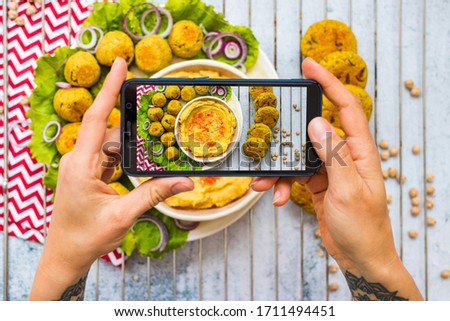 Phone vegan food photo - chickpea hummus and falafel balls. Create blog content photography with smartphone. Overhead, flat lay picture.