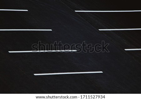 Empty parking during quarantine in the city. White markings for cars on black asphalt.