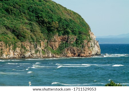 seascape, a beautiful view of the rocky cliff in the sea with mountains on the horizon