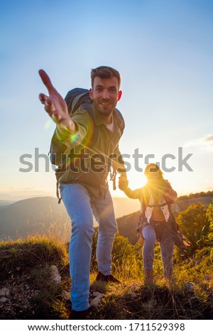 People helping each other hike up a mountain at sunrise. Royalty-Free Stock Photo #1711529398