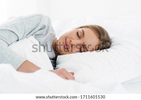 Image closeup of cute young caucasian woman with blonde hair lying and sleeping in bed
