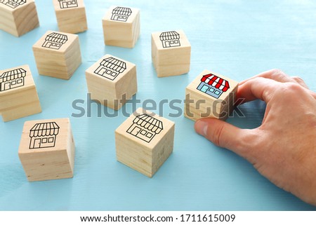 person choosing wooden cube with store sign. concept of choosing brand over others