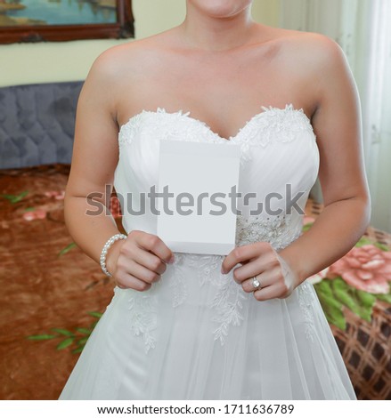 Bride wearing a white gown. Preparations before the wedding ceremony. The bride is holding a white card in her hands