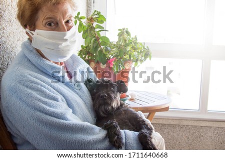 Portrait of senior woman with disposable medical mask and her dog. Safety in public places during the coronavirus outbreak.