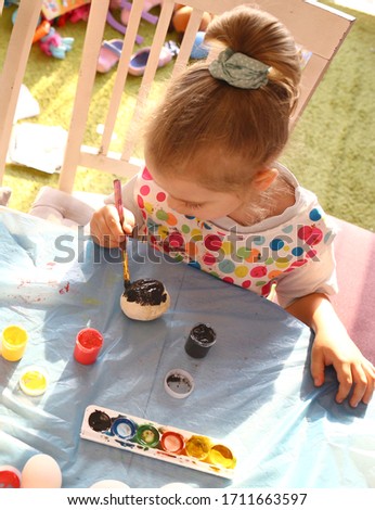 Cute girl with a brush for painting paints the salted dough pots at home. Creative creativity concept for children. Childhood. Normal quarantined life with coronavirus. Lifestyle COVID-19