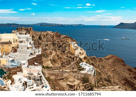 View of Oia city in sunny weather. The background is a blue sky with white clouds. City on Santorini island in Greece.