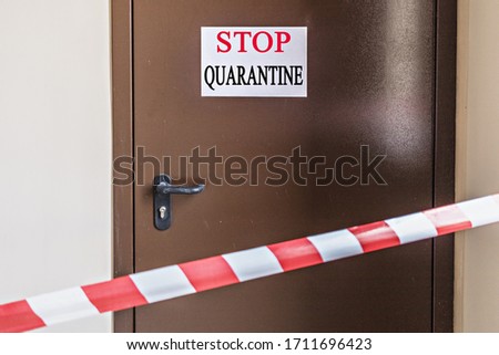 An iron door in the hospital with a warning sign "STOP.KARANTIN" behind the signal forbidden tape. Coronavirus Pandemic, Covid-19.