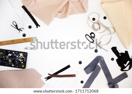 Sewing accessories and fabric on a white background. Sewing threads, needles, pins, fabric, buttons and sewing centimeter. top view, flatlay