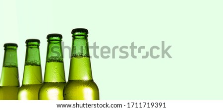 Part of green beer bottles on a light green background, free space for text.