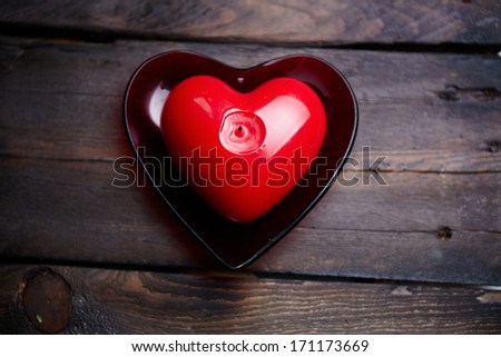 Image of red heart shaped candle on wooden background