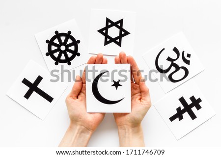 Choose religion concept. Hand with Islam crecent near world religions symbols on white background top view