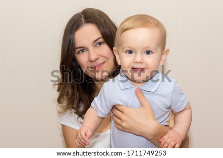 Beautiful Woman holding small cute Baby isolated on light background. Portrait of Beautiful Mother with her Son.