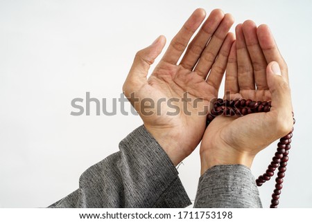 gesture of hand open arm while pray in islamic culture carrying prayer beads over white background Royalty-Free Stock Photo #1711753198