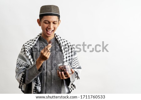 muslim male with a bowl of dates fruit over white background eating for iftar breaking fast